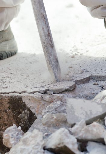 man breaking up a concrete slab with a jackhammer